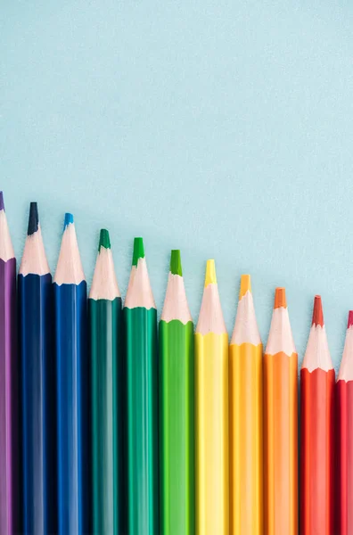 Vista superior de los lápices multicolores del arco iris dispuestos en línea diagonal sobre fondo azul, concepto lgbt - foto de stock