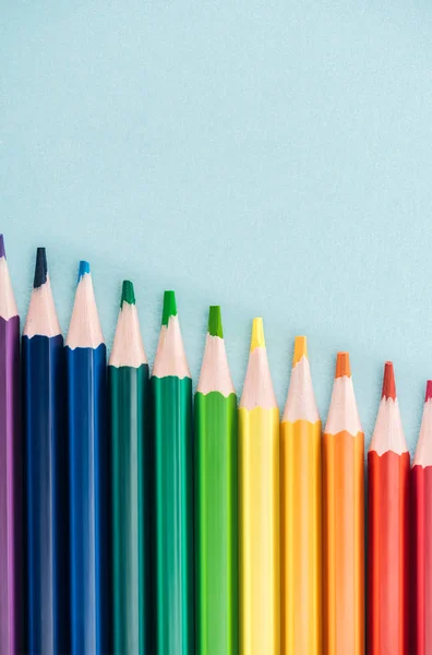 Top view of rainbow multicolored pencils arranged in diagonal line on blue background, lgbt concept — Stock Photo