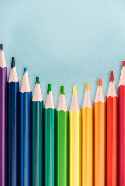 Vue du dessus des crayons multicolores arc-en-ciel sur fond bleu, concept lgbt — Stock Photo