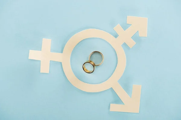 Signo de género de papel blanco con anillos de boda sobre fondo azul, concepto lgbt - foto de stock