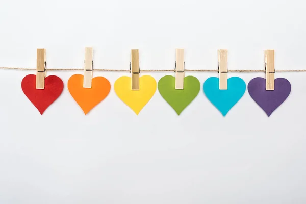 Coração de papel multicolorido arco-íris na corda isolada em branco, conceito lgbt — Fotografia de Stock