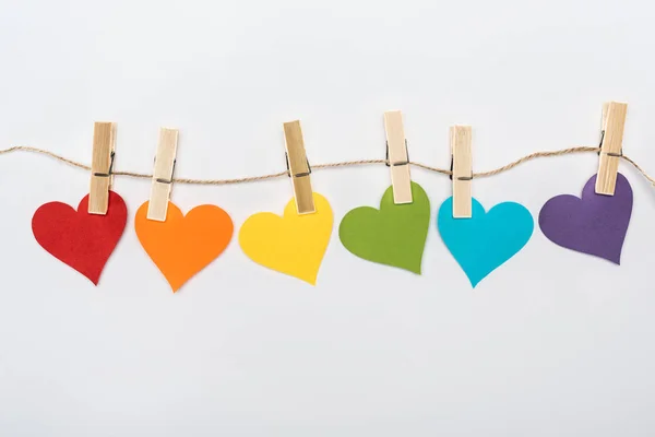 Coeurs en papier multicolore arc-en-ciel sur corde isolé sur blanc, concept lgbt — Photo de stock