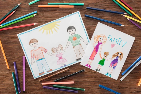Color pencils and felt pens, and white papers with drawings of same sex families and 