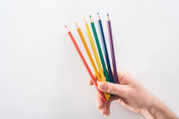 Vista ritagliata di mano maschile con matite colorate arcobaleno su sfondo grigio, concetto lgbt — Foto stock