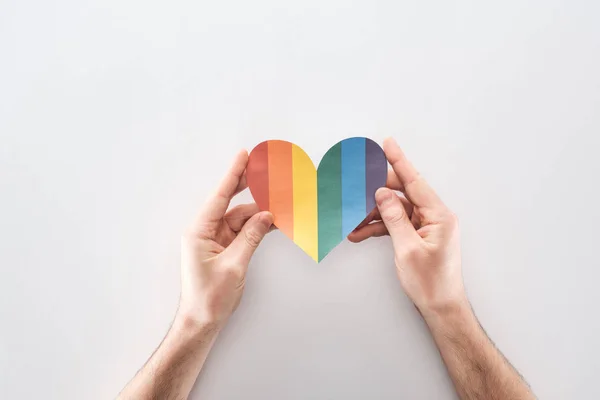 Partial view of man holding rainbow colored paper heart on grey background, lgbt concept — Stock Photo