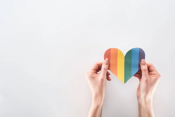 Partial view of woman holding paper rainbow colored paper on grey background, lgbt concept — Stock Photo