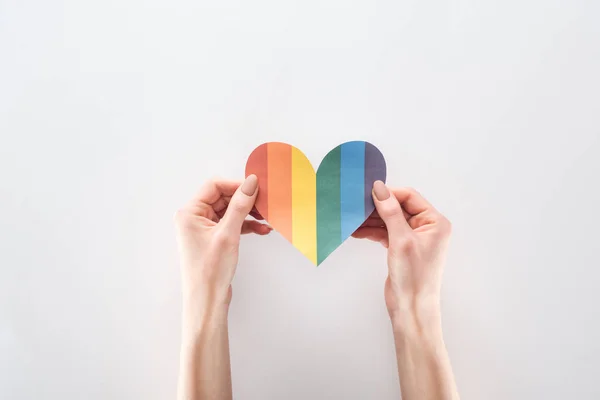 Partial view of woman holding rainbow colored paper heart on grey background, lgbt concept — Stock Photo