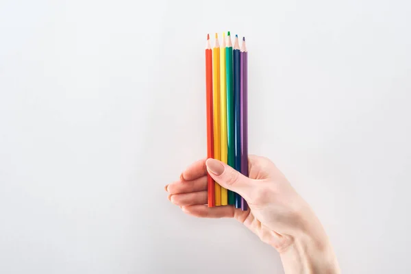 Vue partielle de la main féminine avec crayons de couleur arc-en-ciel isolés sur gris, concept lgbt — Photo de stock