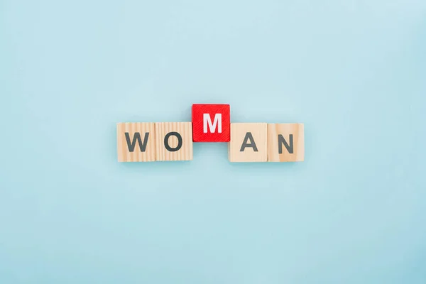 Top view of woman lettering made of wooden blocks on blue background — Stock Photo