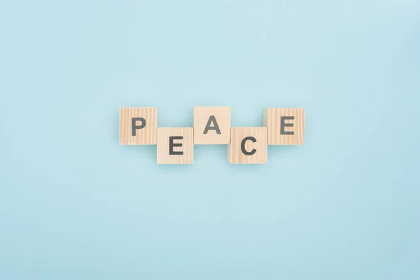 Vista superior de letras de paz hechas de bloques de madera sobre fondo azul - foto de stock