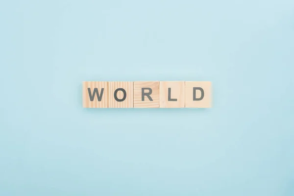 Vista dall'alto del mondo lettering fatta di blocchi di legno su sfondo blu — Foto stock