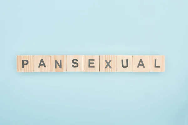 Top view of pansexual lettering made of wooden cubes on blue background — Stock Photo