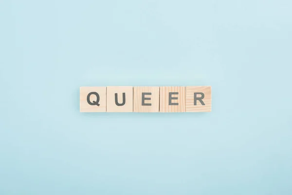 Top view of queer lettering made of wooden cubes on blue background — Stock Photo