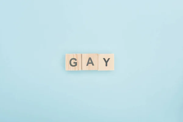 Vista superior de letras gay hechas de cubos de madera sobre fondo azul - foto de stock