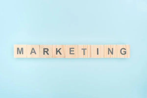 Top view of marketing lettering made of wooden cubes on blue background — Stock Photo