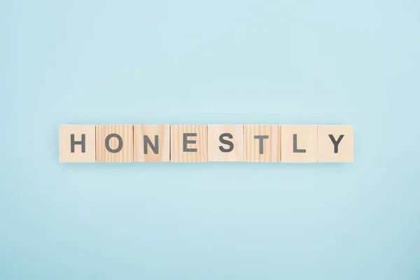 Top view of honestly lettering made of wooden cubes on blue background — Stock Photo