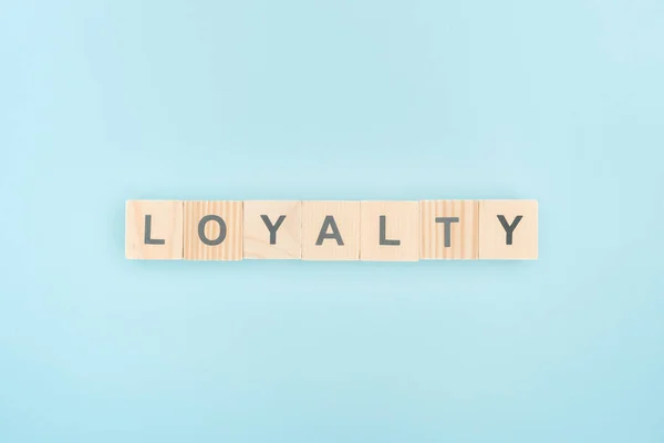 Вид зверху написання лояльності з дерев'яних кубиків на синьому фоні — стокове фото