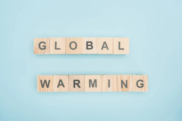 Top view of global warming lettering made of wooden cubes on blue background — Stock Photo