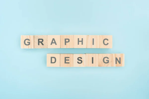 Draufsicht auf Grafik-Design-Schriftzug aus Holzwürfeln auf blauem Hintergrund — Stockfoto