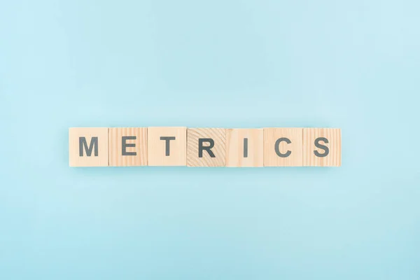 Vista superior de letras métricas hechas de cubos de madera sobre fondo azul — Stock Photo