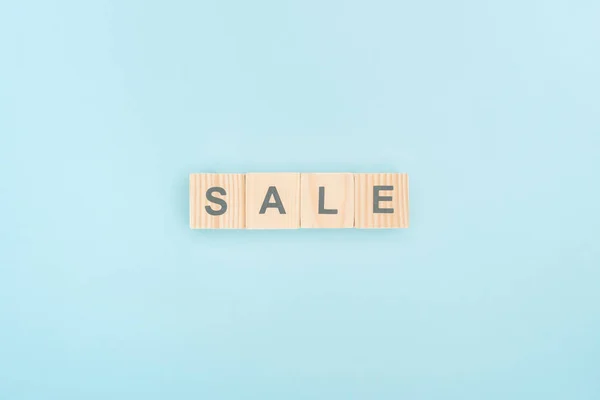 Top view of sale lettering made of wooden cubes on blue background — Stock Photo