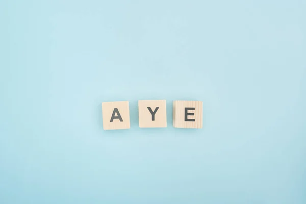 Top view of aye lettering made of wooden cubes on blue background — Stock Photo