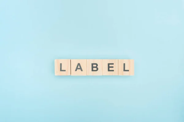 Top view of lable lettering made of wooden cubes on blue background — Stock Photo