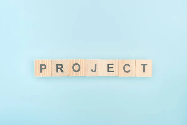 Ansicht des Projektschriftzugs aus Holzwürfeln auf blauem Hintergrund — Stockfoto