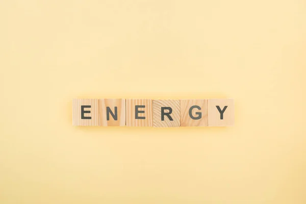 Top view of energy lettering made of wooden cubes on yellow background — Stock Photo