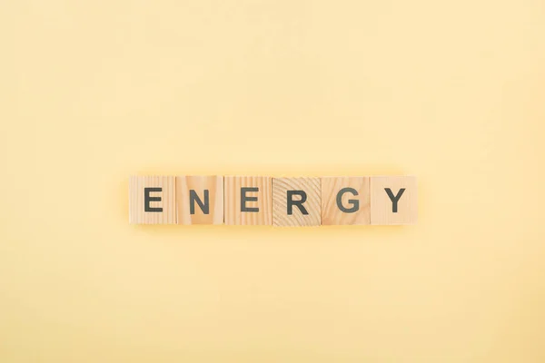 Vista superior de letras de energía hechas de cubos de madera sobre fondo amarillo — Stock Photo