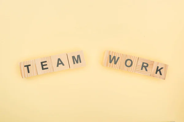 Vista dall'alto del lavoro di squadra lettering fatta di cubi di legno su sfondo giallo — Foto stock