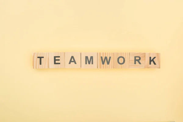 Draufsicht auf Teamarbeit Schriftzug aus Holzklötzen auf gelbem Hintergrund — Stockfoto