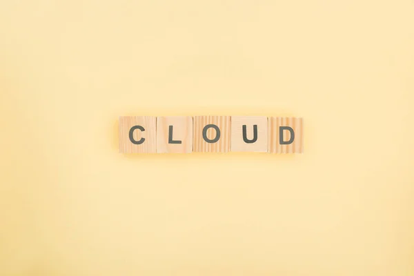 Top view of cloud lettering made of wooden cubes on yellow background — Stock Photo