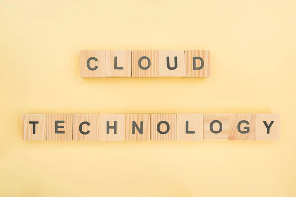 Vista dall'alto della tecnologia cloud lettering fatta di cubi di legno su sfondo giallo — Foto stock