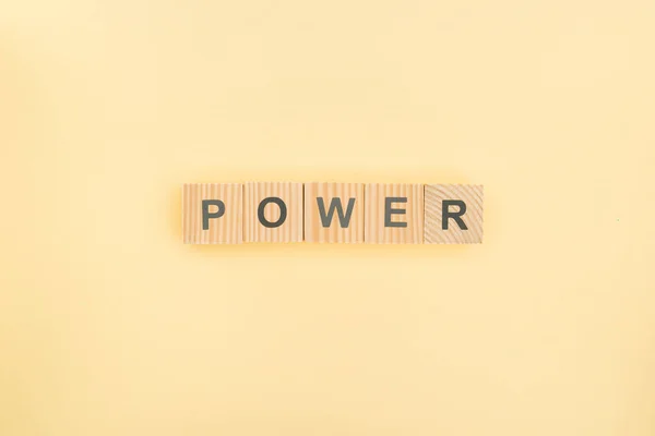 Top view of power lettering made of wooden cubes on yellow background — Stock Photo