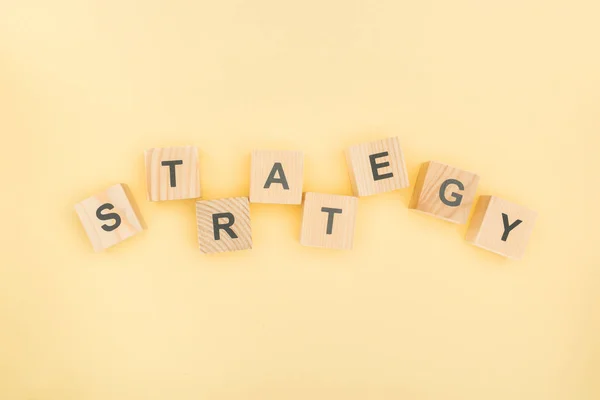 Top view of strategy lettering made of wooden blocks on yellow background — Stock Photo