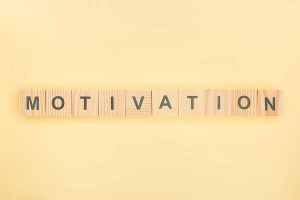 Top view of motivation lettering made of wooden cubes on yellow background — Stock Photo