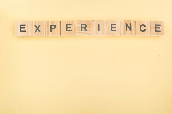 Top view of experience lettering made of wooden blocks on yellow background — Stock Photo