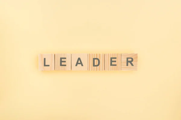 Top view of leader lettering made of wooden cubes on yellow background — Stock Photo