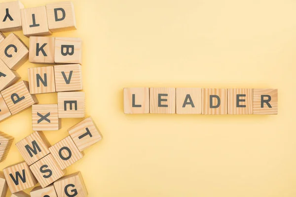 Vue du dessus du lettrage de leader avec des cubes en bois sur fond jaune — Photo de stock