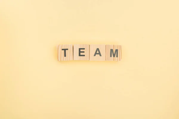 Top view of team lettering made of wooden cubes on yellow background — Stock Photo