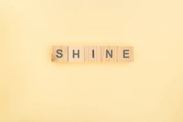 Top view of shine lettering made of wooden cubes on yellow background — Stock Photo