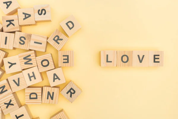 Vista superior de letras de amor con cubos de madera sobre fondo amarillo - foto de stock