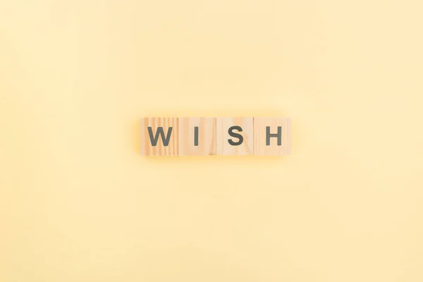 Top view of wish lettering made of wooden blocks on yellow background — Stock Photo