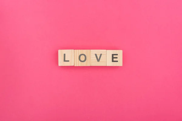 Vista superior de letras de amor feitas de blocos de madeira sobre fundo rosa — Fotografia de Stock
