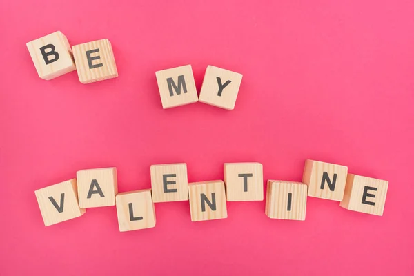 Vue du dessus de être mon lettrage de Saint-Valentin en blocs de bois sur fond rose — Photo de stock