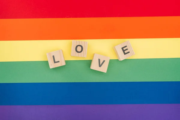 Vista dall'alto di amore lettering fatto di cubi di legno su sfondo arcobaleno di carta — Foto stock
