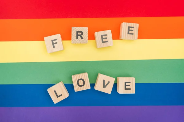 Vista dall'alto del lettering amore libero fatto di cubi di legno su sfondo arcobaleno di carta — Foto stock