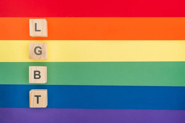Top view of lgbt lettering made of wooden cubes on paper rainbow background — Stock Photo