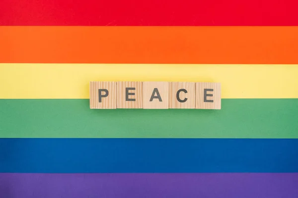 Vista superior de paz pease lettering feito de cubos de madeira sobre papel arco-íris fundo — Fotografia de Stock